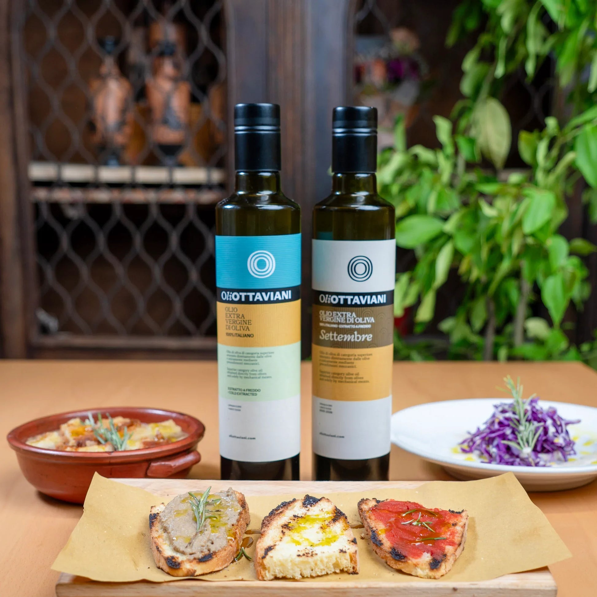 Bottiglie di olio extra vergine di oliva Olio Ottaviani con bruschette e piatti di contorno